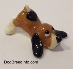 The front right side of a brown with white and black Hound Dawg figurine. The figurine has a black circle for a nose.
